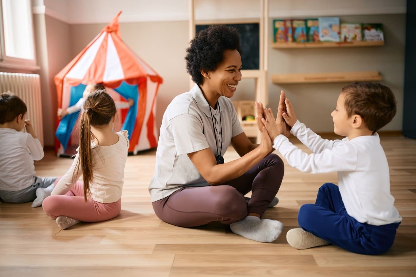 Educadora interagindo com crianças pequenas em uma sala de educação infantil, respeitando o ritmo e a participação de cada criança nas atividades.