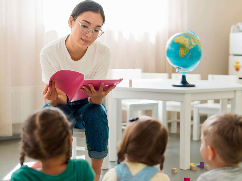 Foto de uma professora lendo uma história para crianças em uma escola