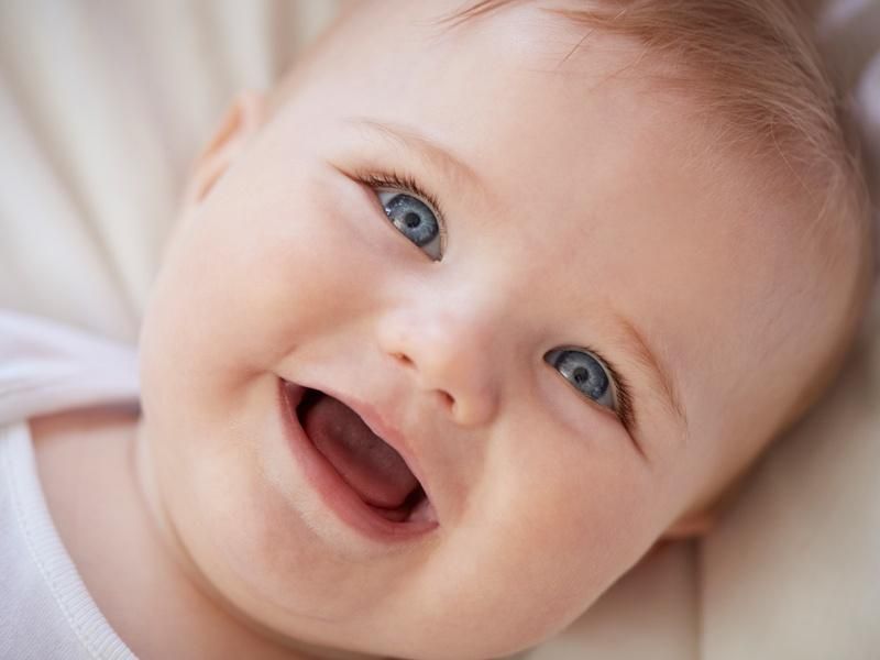 Bebê branco loiro de olhos azuis sorrindo e olhando pra cima