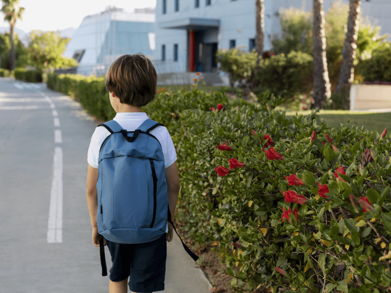 Menino branco de mochila indo para a escola
