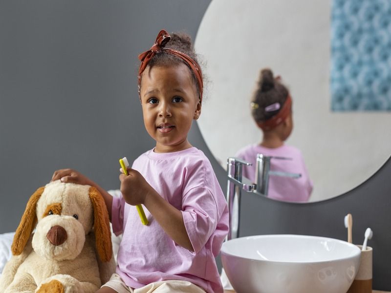 Bebê segurando uma escova de dentes e um cachorro de pelúcia em um banheiro