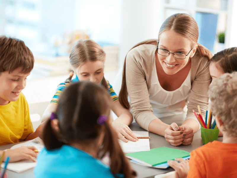 Professora branca ensinando crianças em uma escola