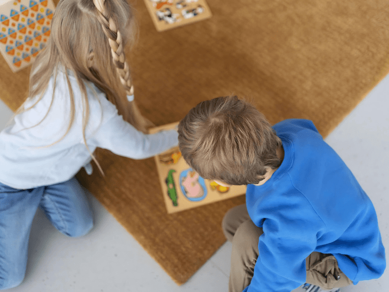 Duas crianças loiras brincando num tapete