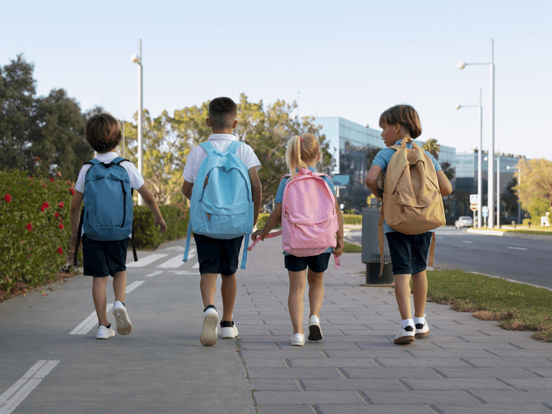Quatro crianças de mochila indo para a escola